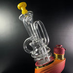 Clear / yellow puffco peak recycler sitting on a daybreak Puffco Peak Pro