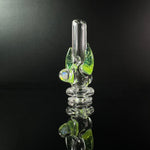 Clear puffco pivot glass mouthpiece with opal and green horns, against a black backround